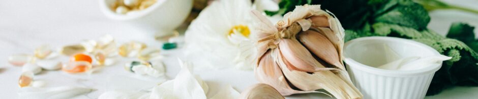 Flat lay of garlic, supplements, and herbs showcasing natural remedies on a marble surface.